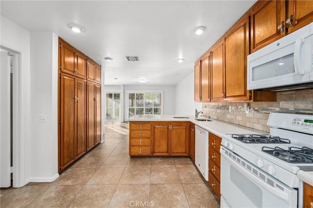 kitchen with white appliances, kitchen peninsula, light tile patterned floors, and backsplash