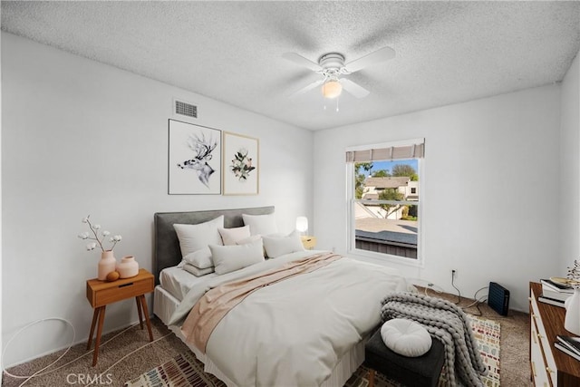 bedroom with ceiling fan, carpet, and a textured ceiling