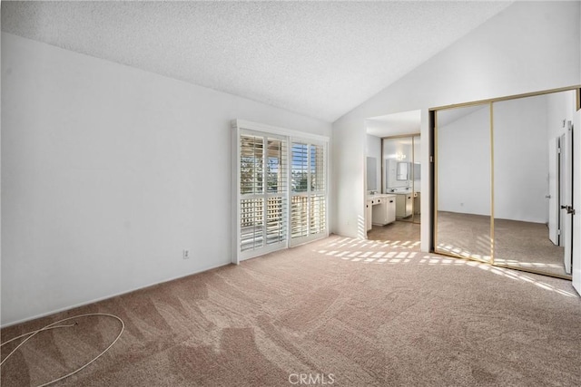 unfurnished bedroom featuring ensuite bathroom, a textured ceiling, access to outside, carpet flooring, and a closet