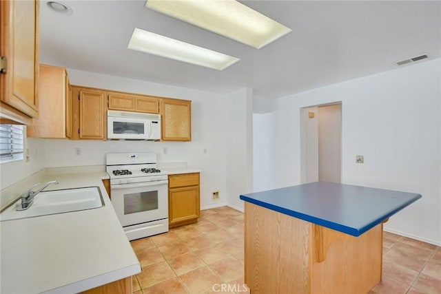 kitchen with a center island, sink, light tile patterned floors, and white appliances