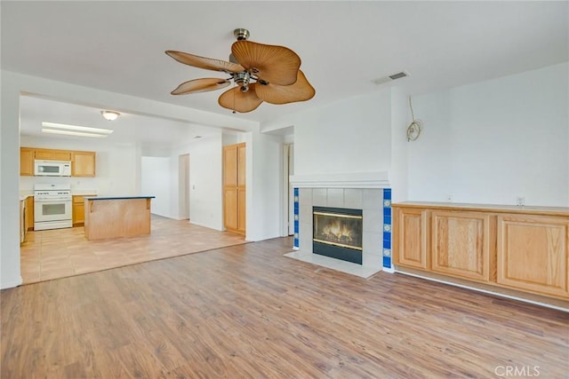 unfurnished living room with ceiling fan, a fireplace, and light hardwood / wood-style floors