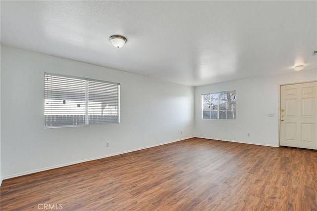 unfurnished room with dark wood-type flooring and plenty of natural light