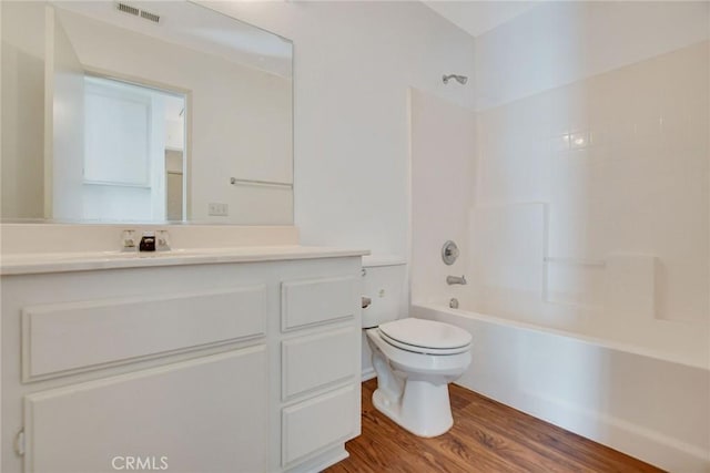 full bathroom featuring hardwood / wood-style flooring, washtub / shower combination, vanity, and toilet