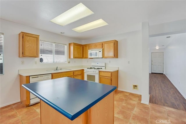 kitchen with sink, white appliances, a center island, and light tile patterned flooring