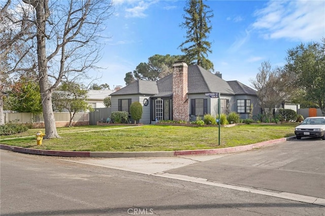 view of front of home featuring a chimney, fence, and a front yard