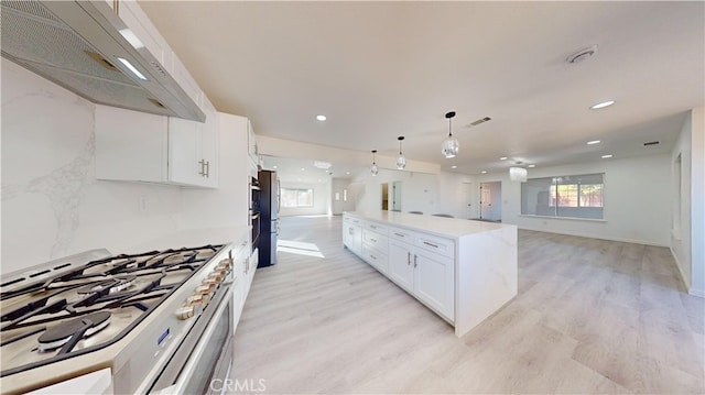 kitchen with light hardwood / wood-style flooring, range hood, gas range, pendant lighting, and white cabinetry