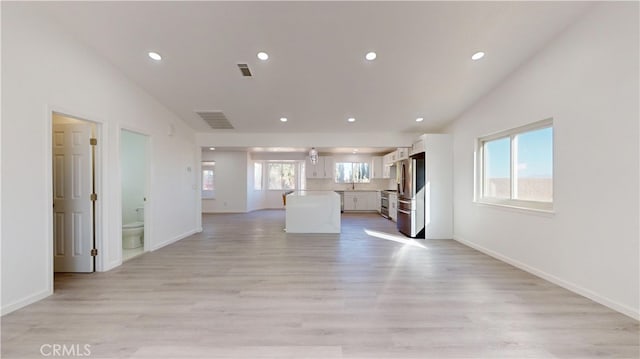 unfurnished living room with light hardwood / wood-style floors and vaulted ceiling