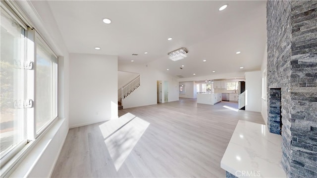 living room featuring light wood-type flooring, vaulted ceiling, and a fireplace