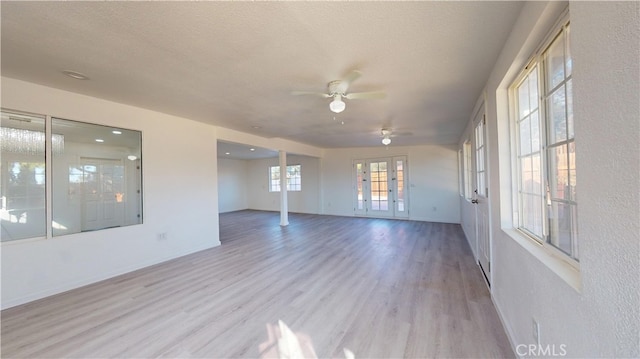 interior space with ceiling fan, light hardwood / wood-style flooring, french doors, and a textured ceiling