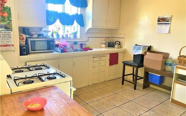 26302632 L St Unit A, B, C, Bakersfield, CA 93301 - kitchen featuring stainless steel microwave, white gas stove, light tile patterned floors, tile counters, and decorative backsplash