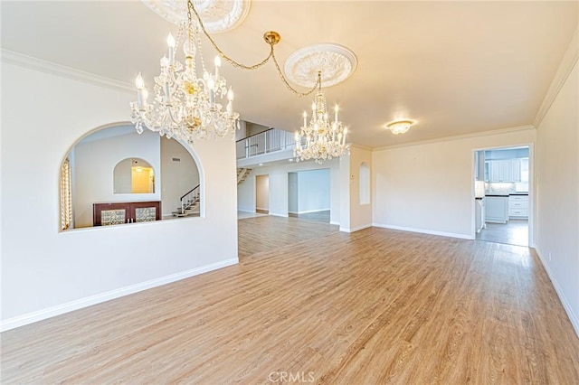 empty room featuring a notable chandelier, crown molding, and hardwood / wood-style floors