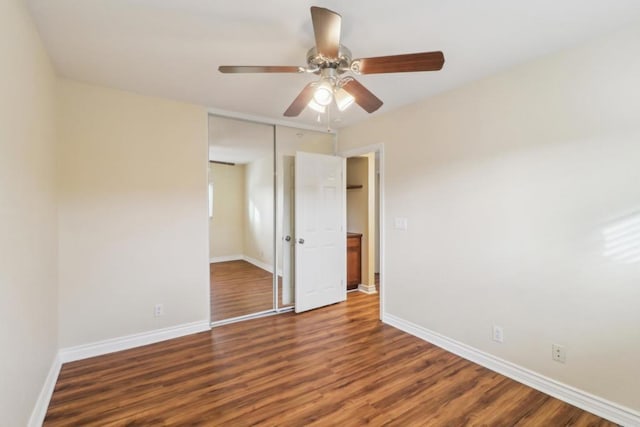 unfurnished bedroom featuring dark wood-type flooring, ceiling fan, and a closet