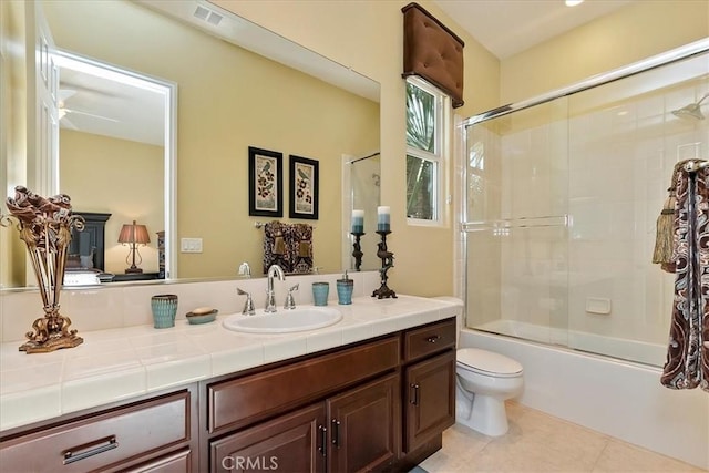 full bathroom featuring tile patterned flooring, vanity, bath / shower combo with glass door, and toilet