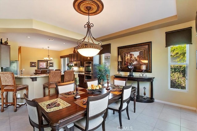 tiled dining area featuring a notable chandelier and a raised ceiling