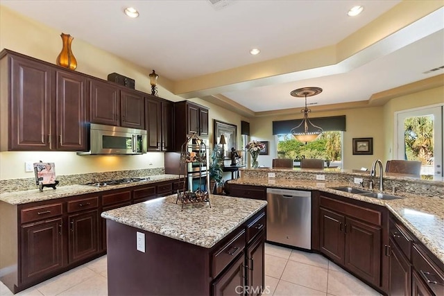 kitchen with pendant lighting, sink, appliances with stainless steel finishes, a center island, and kitchen peninsula