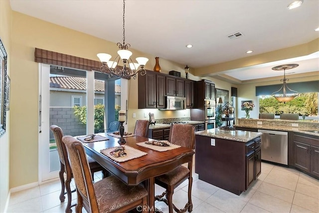 tiled dining room featuring plenty of natural light and a chandelier