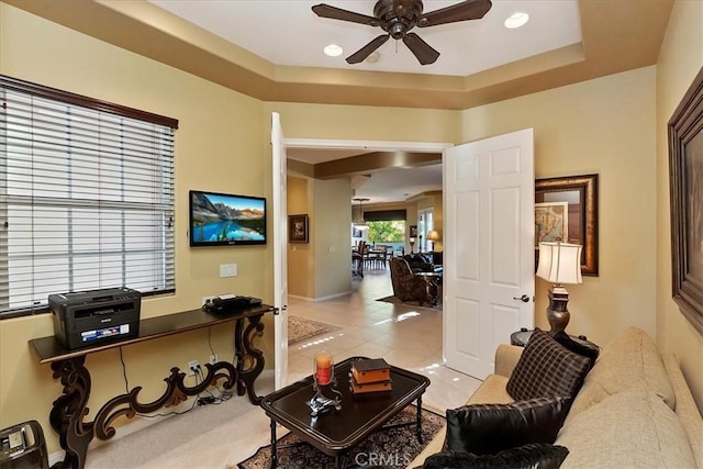 home office with ceiling fan, a raised ceiling, and light tile patterned floors