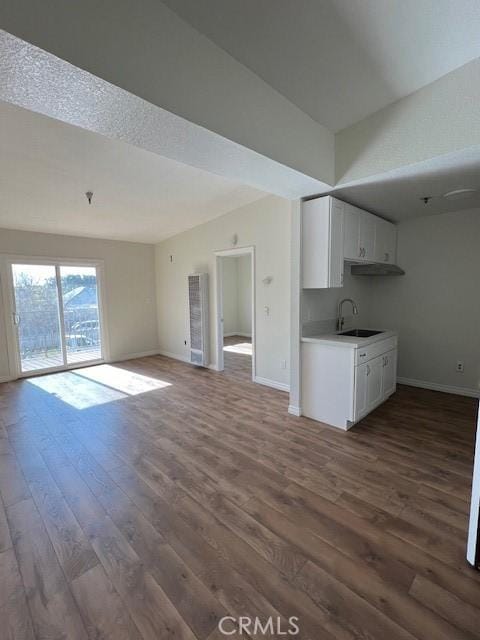 unfurnished living room with dark wood-style floors, a sink, and baseboards