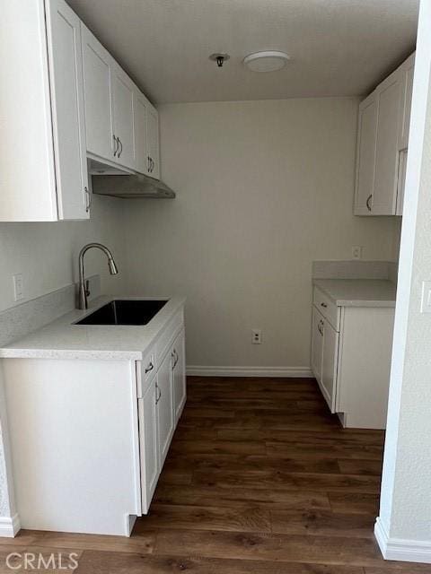 kitchen featuring dark wood-type flooring, light countertops, white cabinets, and a sink