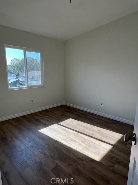 spare room with dark wood-style flooring and baseboards