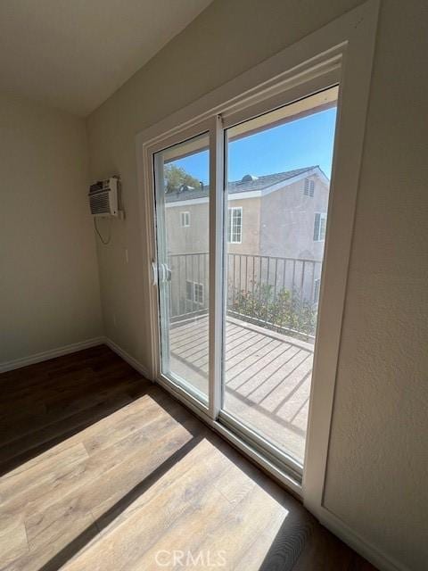 doorway with an AC wall unit, dark wood finished floors, and baseboards