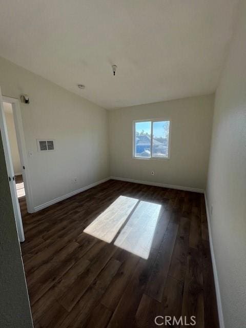 empty room with dark wood-style floors, baseboards, and visible vents