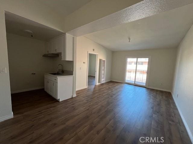 interior space with dark wood finished floors, a sink, white cabinetry, and baseboards