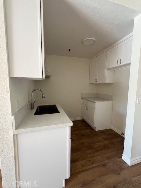 kitchen featuring dark wood-style floors, light countertops, white cabinets, and a sink