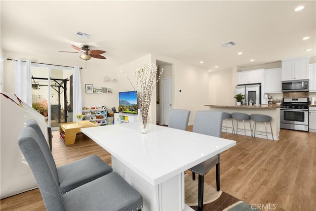 dining space with light hardwood / wood-style floors and ceiling fan