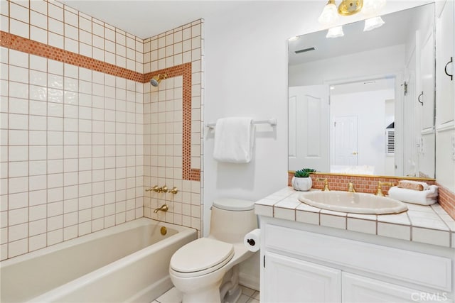 full bathroom featuring vanity, tiled shower / bath combo, and toilet