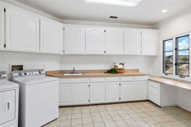 clothes washing area with washer and dryer, light tile patterned flooring, sink, and cabinets