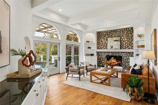 interior space featuring built in shelves, beam ceiling, a fireplace, recessed lighting, and light wood-style flooring