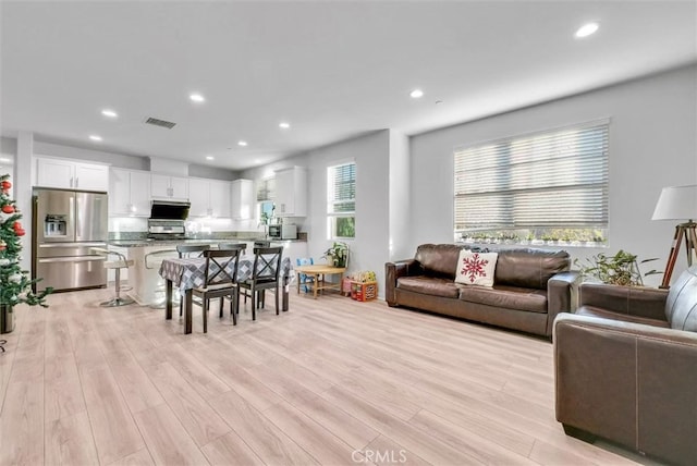 living room featuring light wood-style floors, recessed lighting, visible vents, and plenty of natural light