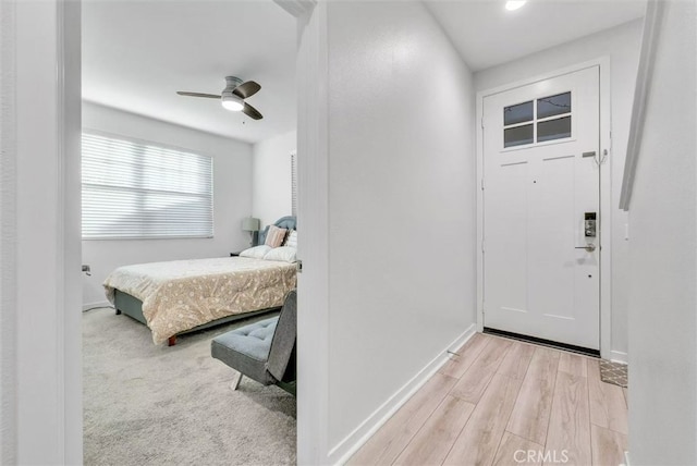 foyer featuring light wood finished floors, baseboards, and a ceiling fan