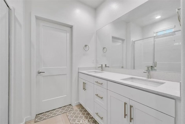 full bath featuring double vanity, a stall shower, tile patterned flooring, and a sink