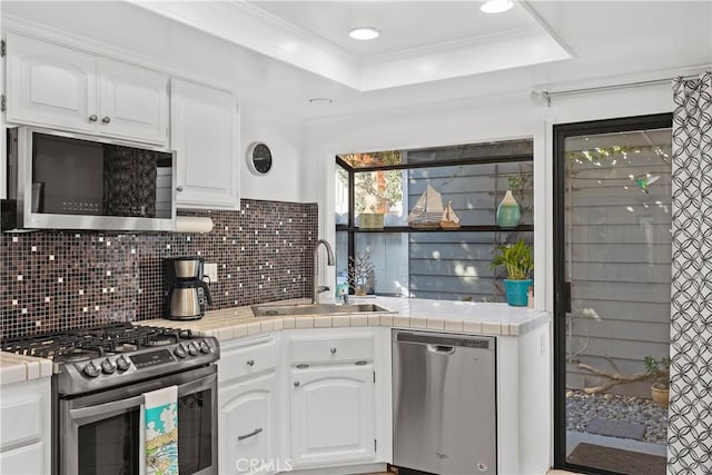 kitchen featuring appliances with stainless steel finishes, tile counters, sink, and white cabinets