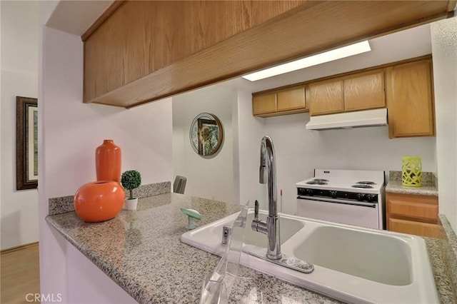 kitchen with white range with electric cooktop, kitchen peninsula, and light stone countertops