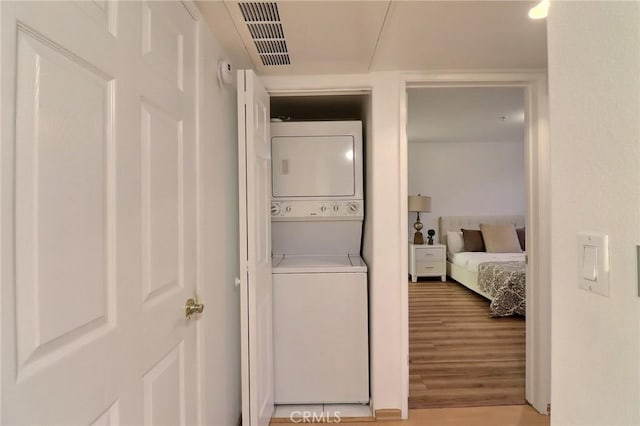 washroom featuring stacked washer and dryer and light hardwood / wood-style flooring