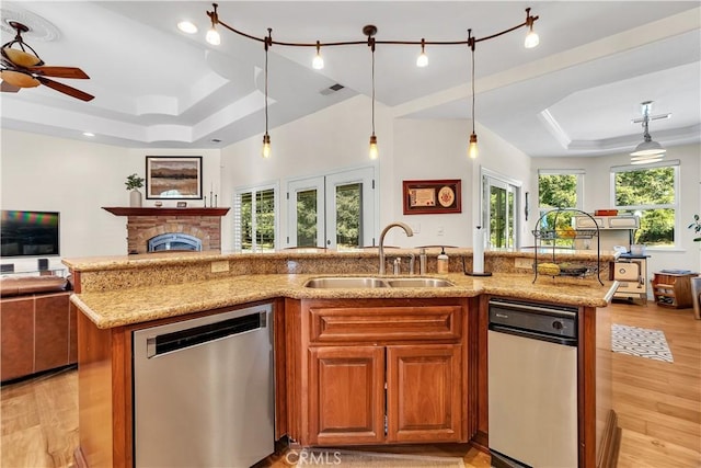 kitchen featuring an island with sink, dishwasher, sink, and a raised ceiling