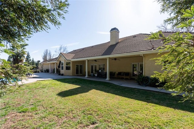 back of property with ceiling fan, a patio area, and a lawn