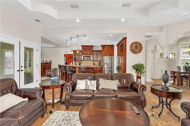 living room featuring decorative columns, light hardwood / wood-style floors, and french doors