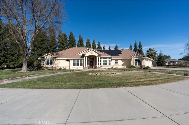 ranch-style house featuring a front yard and solar panels