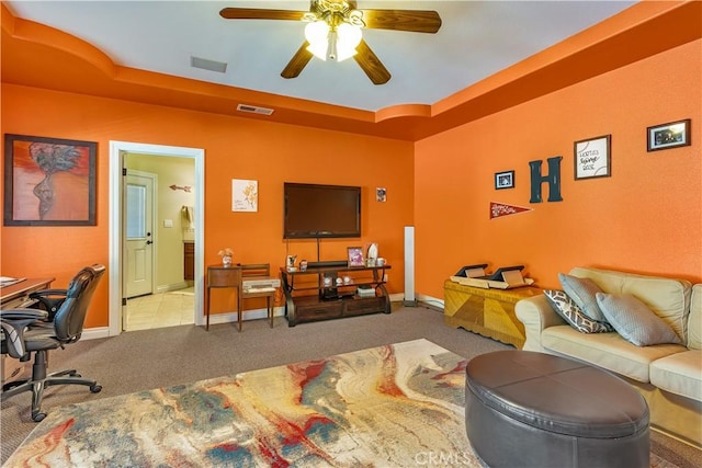 carpeted living room featuring ceiling fan and a tray ceiling