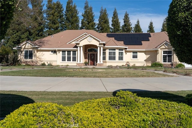 view of front facade featuring a front lawn and solar panels