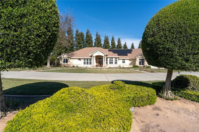 ranch-style home with a front yard and solar panels