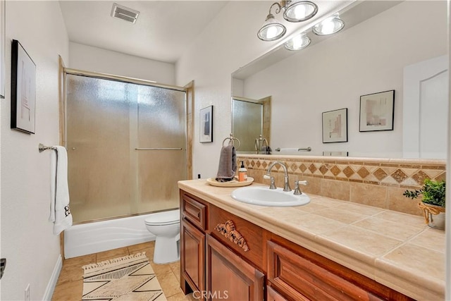 full bathroom featuring tasteful backsplash, shower / bath combination with glass door, vanity, toilet, and tile patterned floors