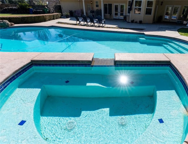 view of swimming pool featuring a patio area and french doors