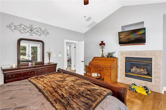 bedroom featuring vaulted ceiling, wood-type flooring, ceiling fan, and a fireplace