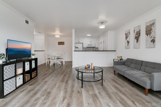 living room with ornamental molding and light wood-type flooring