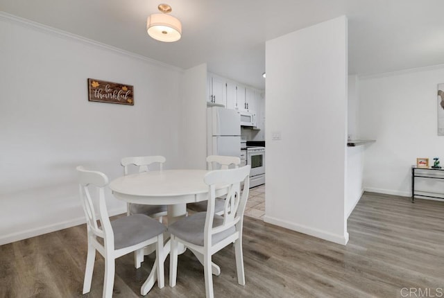 dining area featuring crown molding and light wood-type flooring